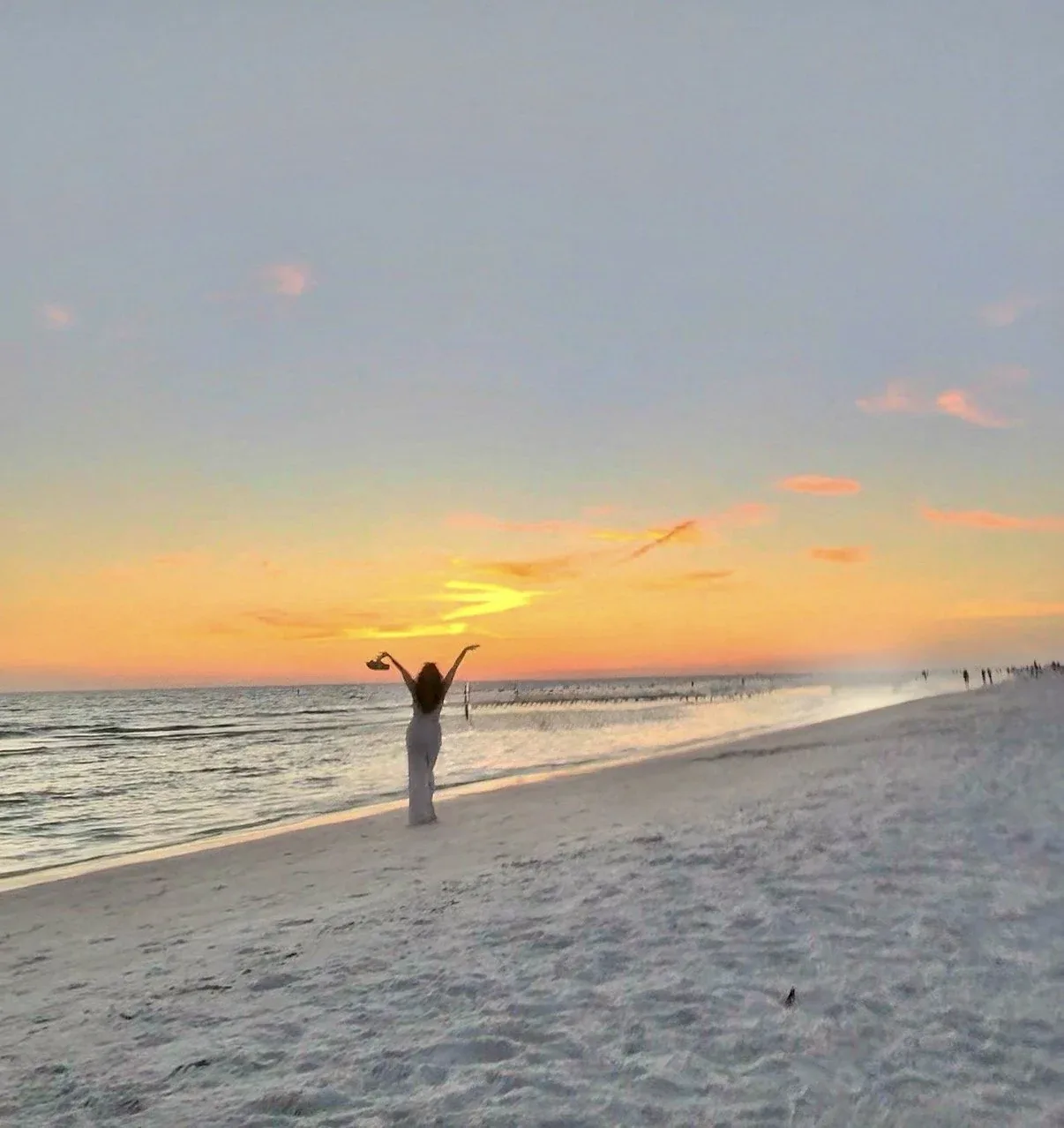 Paige on a Gulf-coast beach at sunset, arms raised
